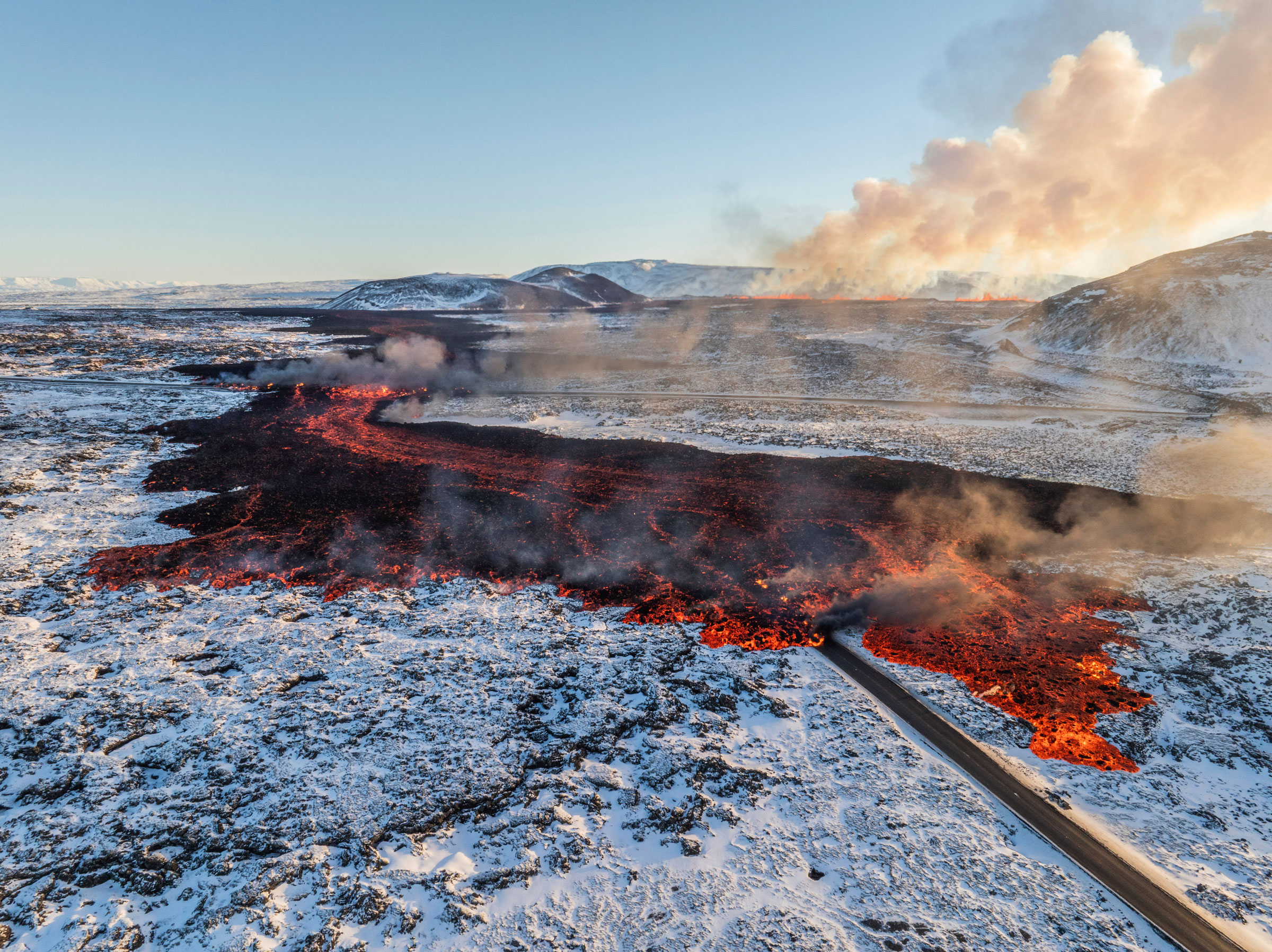A view of lava crossing the main road to Grindavík and flowing on the road leading to the Blue Lagoon, in Grindavík, Iceland