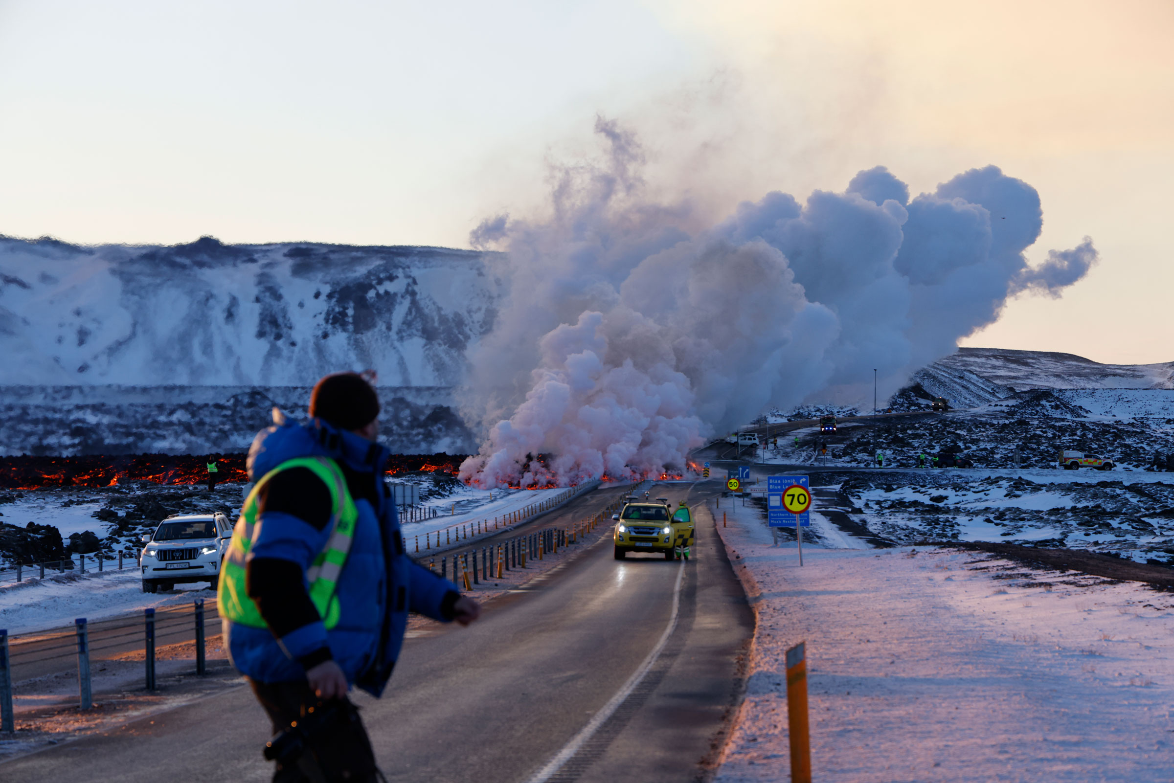 Emergency services close a road as lava erupts from a fissure in Grandavík, Iceland.