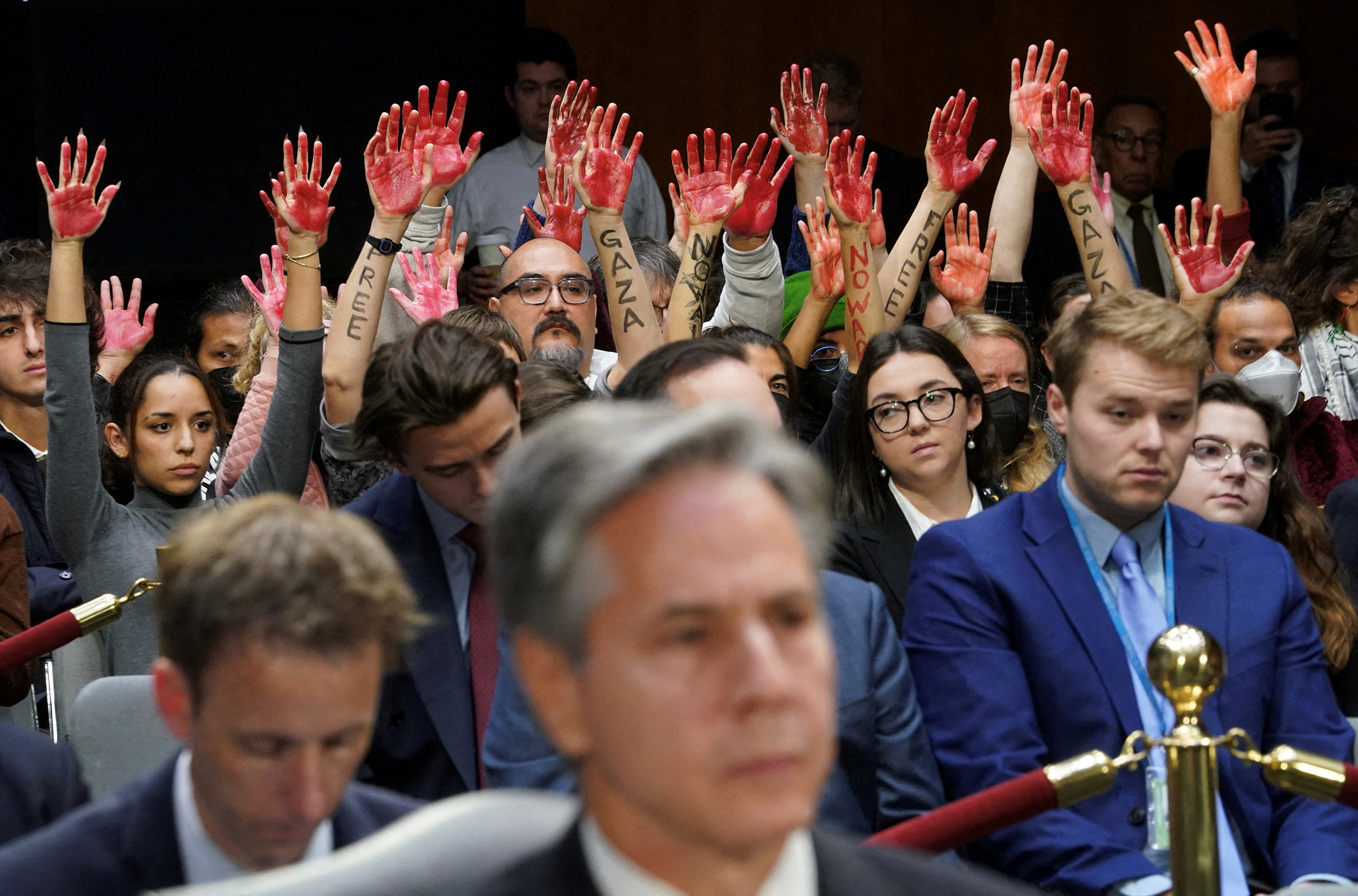 Anti-war protesters raise painted hands behind U.S. Secretary of State Antony Blinken during a Senate Appropriations Committee hearing on President Biden's $106 billion national security supplemental funding request to support Israel and Ukraine, as well as bolster border security, on Capitol Hill in Washington, U.S., on Oct. 31, 2023.