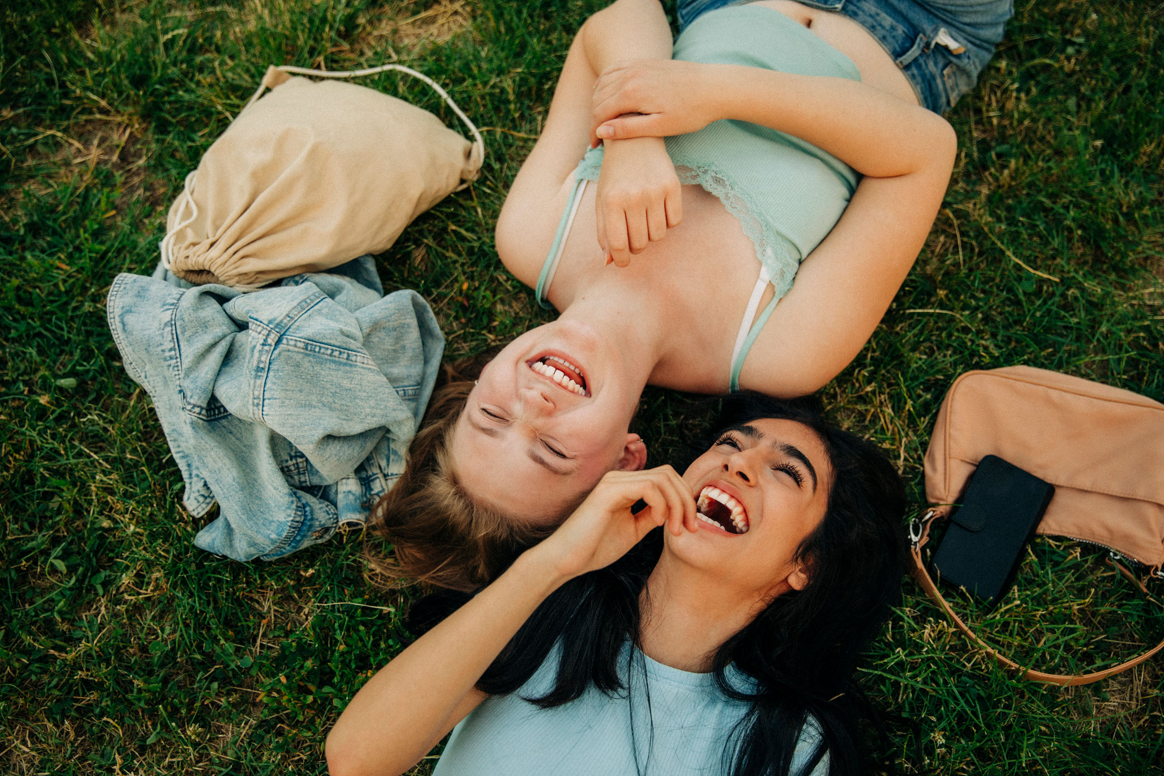 Cheerful teenage girls lying together at park