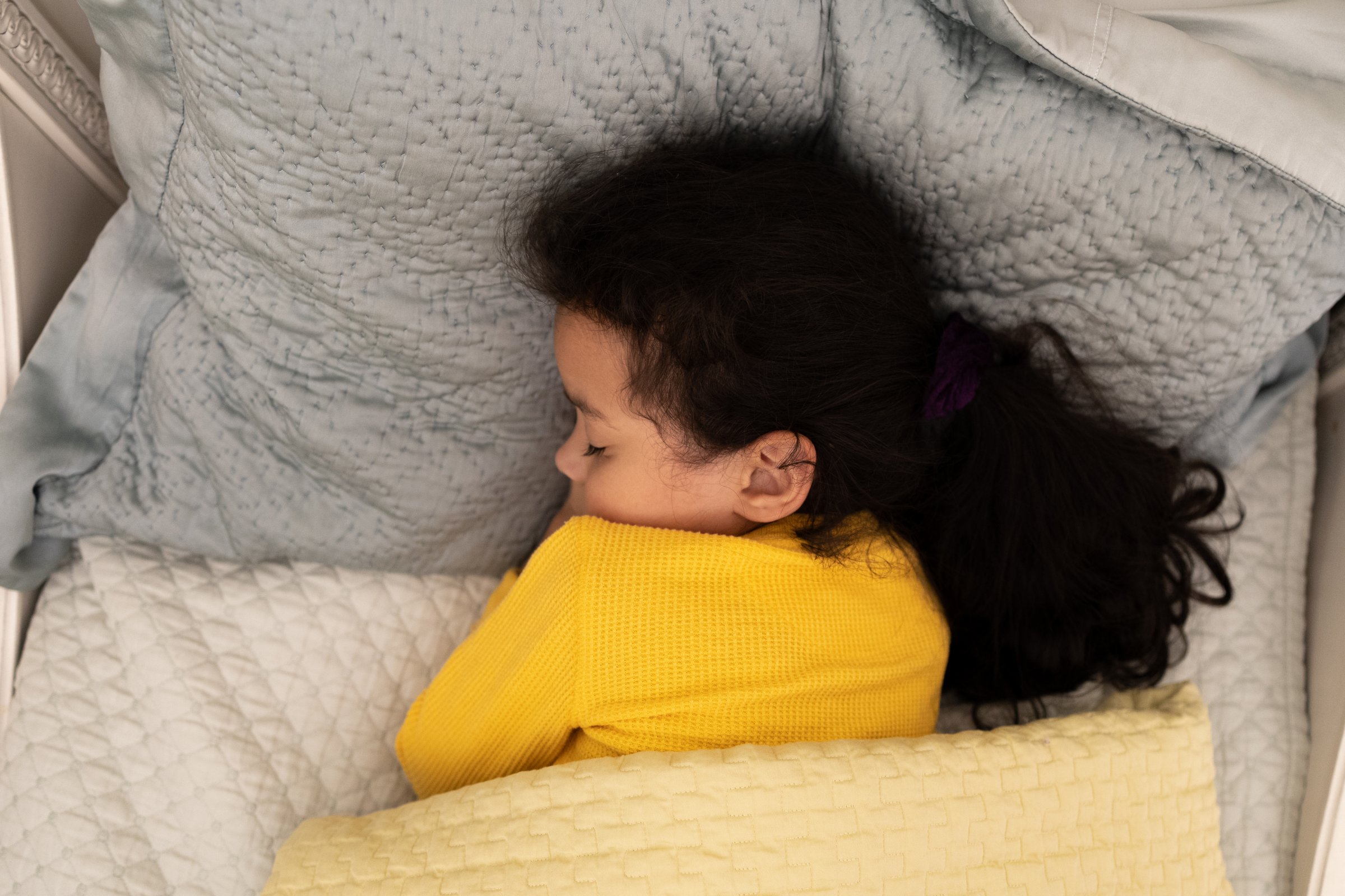 young mixed-race girl soundly sleeping under weighted blanket