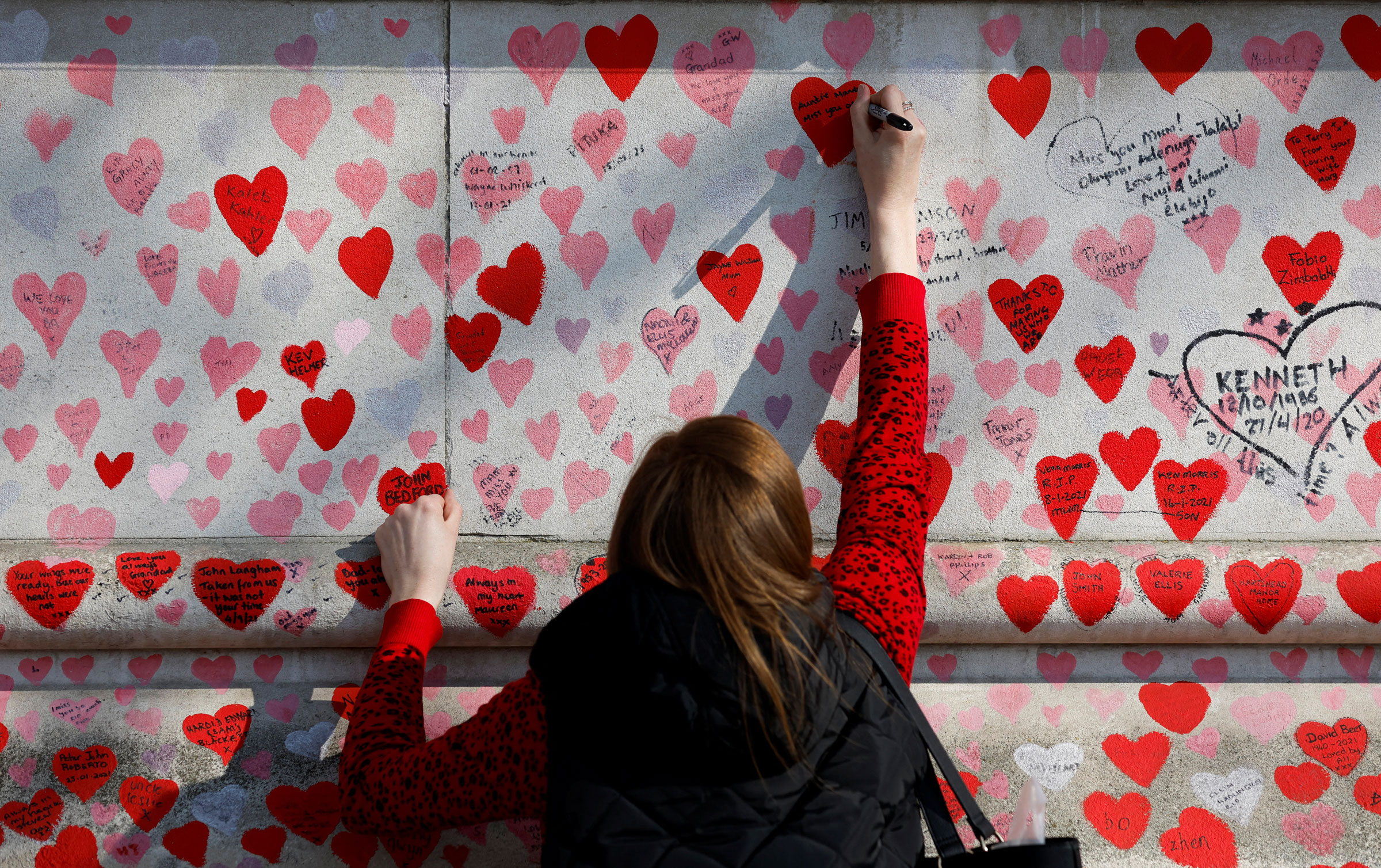 A person writes a message on The National Covid Memorial Wall, on national day of reflection to mark the two year anniversary of the United Kingdom going into national lockdown, in London, on March 23, 2022.