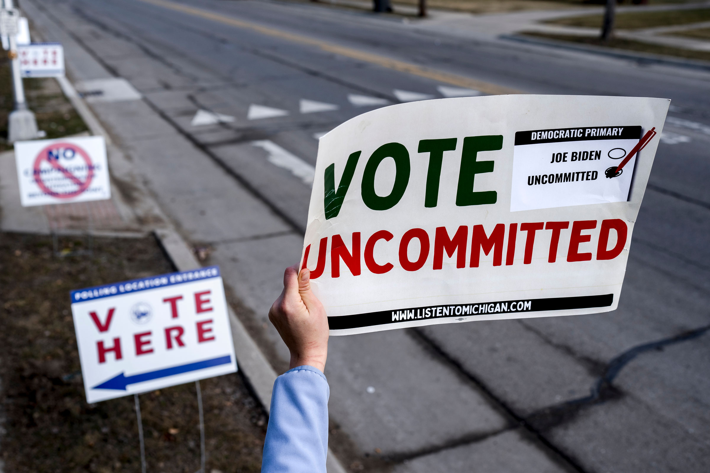 A volunteer holds a “Vote Uncommitted” sign outside of a polling station at Oakman School in Dearborn, Mich., on Feb. 27, 2024.