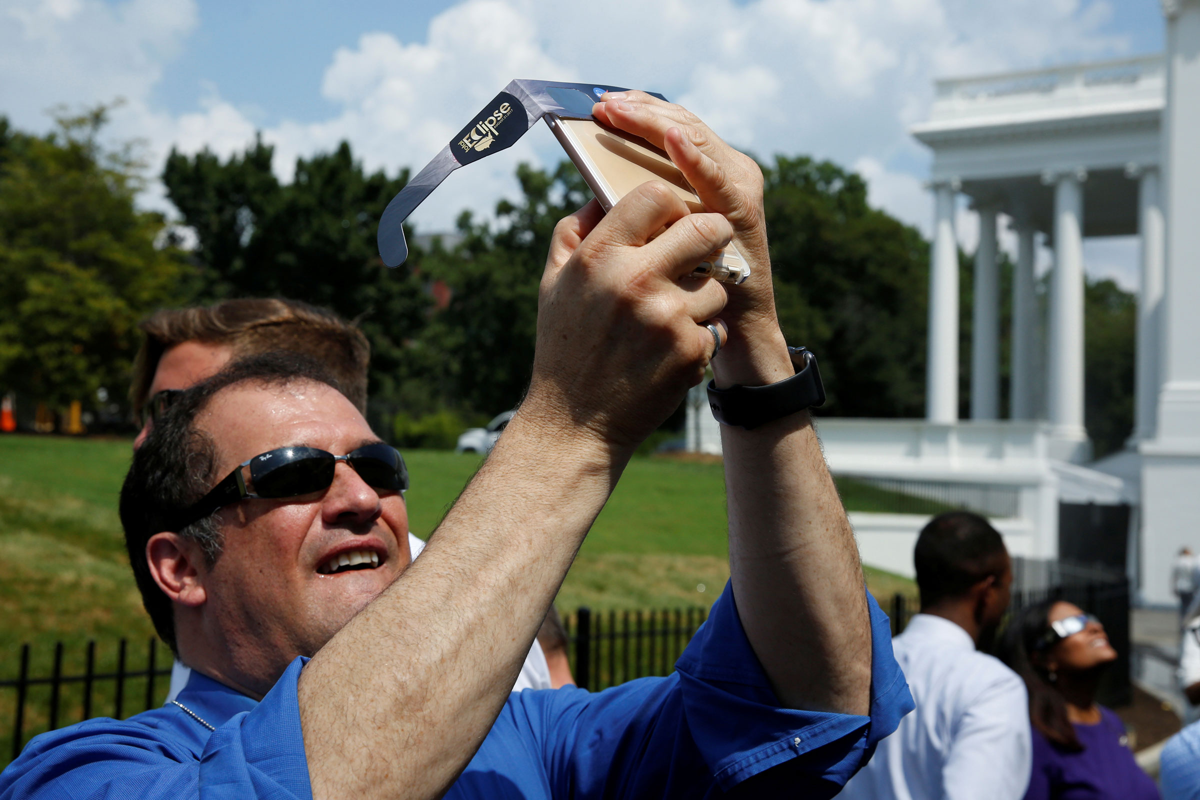Members of the media watch the solar eclipse at the White House in Washington
