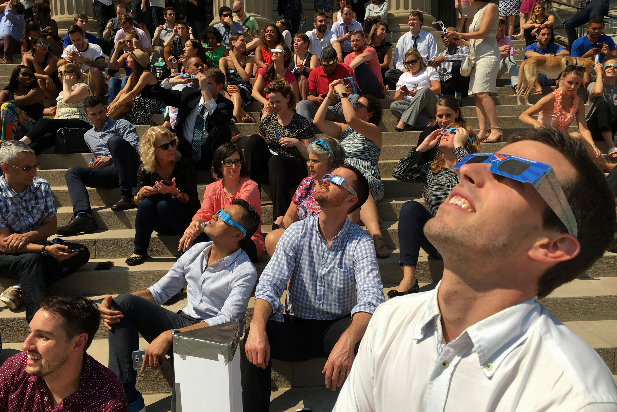 2017 年 8 月 21 日，一群人在华盛顿特区国家城市基督教教堂的台阶上观看日食。