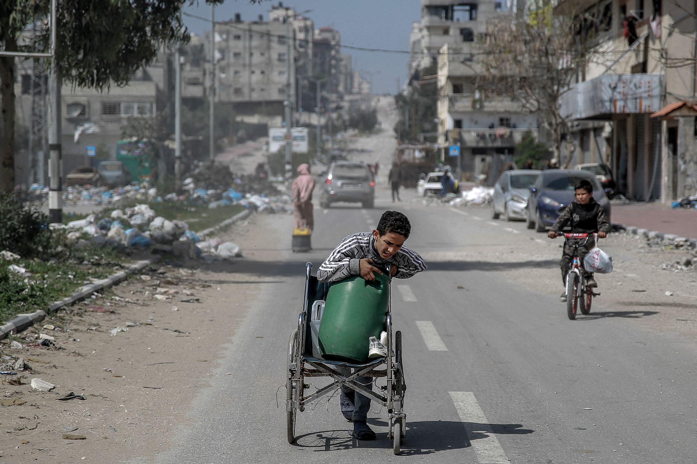 A Palestinian boy transports a water container on a wheelchair along a street in Gaza City on March 3, amid the ongoing conflict between Israel and Hamas.
