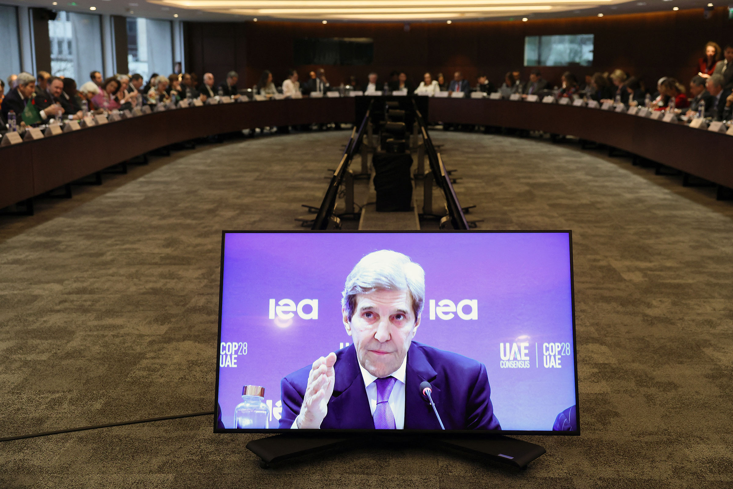 John Kerry is seen on a screen as he speaks during a high-level round table on COP energy and climate commitments organized by the International Energy Agency at its headquarters in Paris on Feb. 20, 2024.