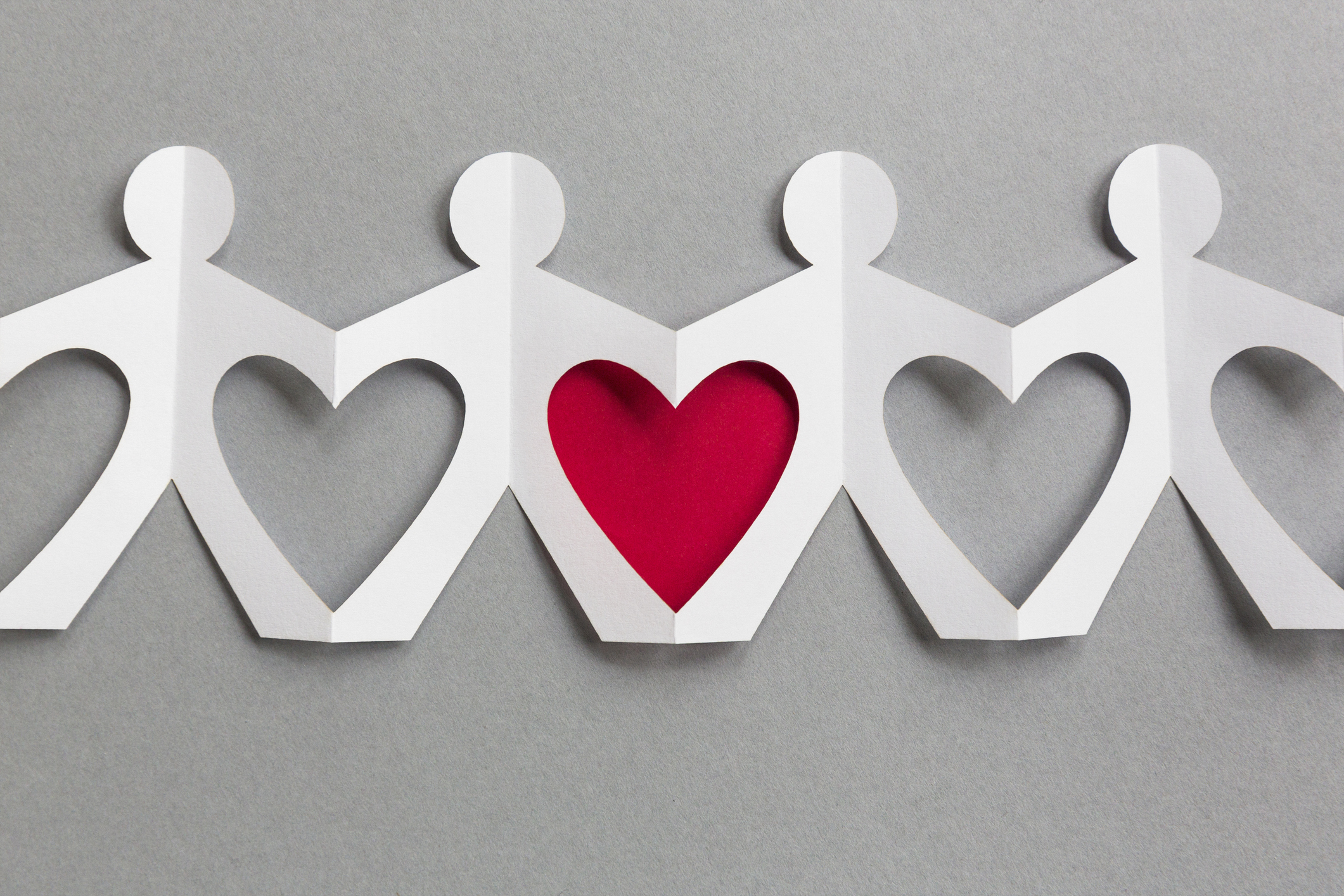 Line of paper cut-out figures forming heart shapes