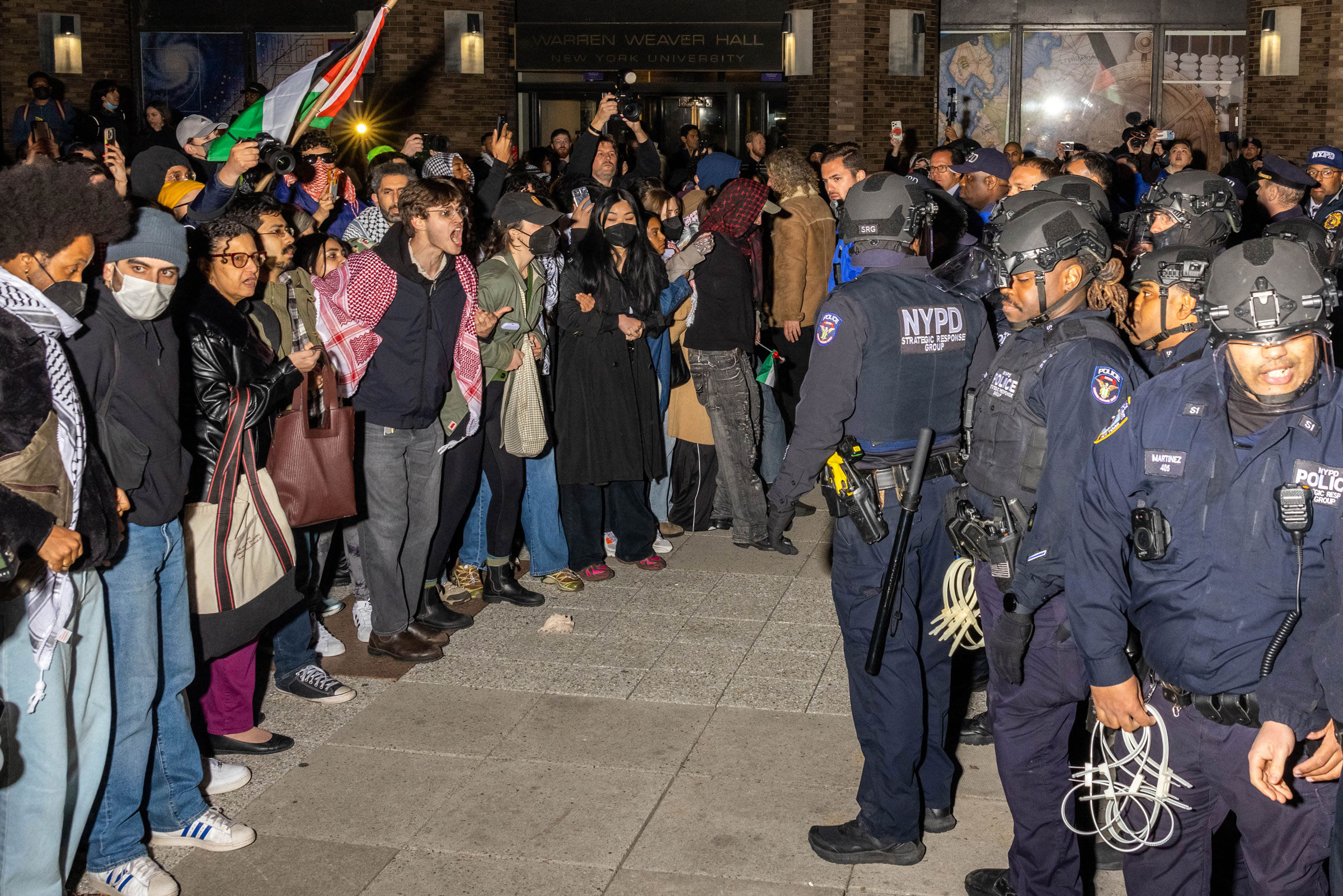 NYPD officers face protesters after detaining demonstrators and clearing an encampment set up by pro-Palestinian students and protesters on the campus of New York University, on April 22, 2024.