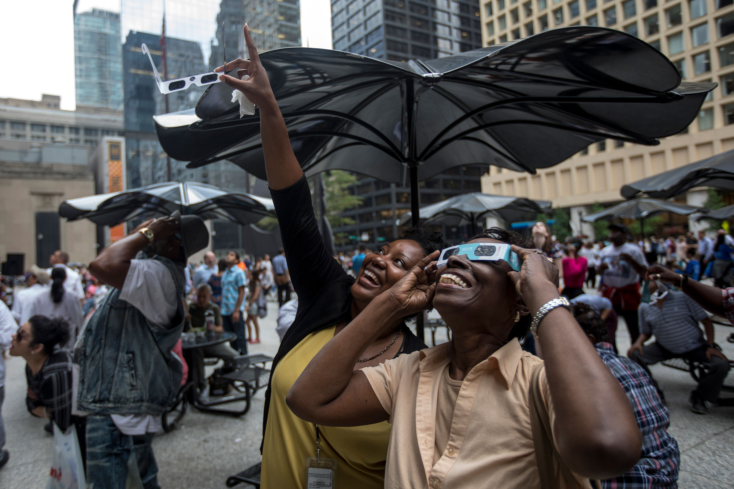 People react as the solar eclipse becomes visible through the clouds in Daley Plaza in downtown Chicago on Aug. 21, 2017.
