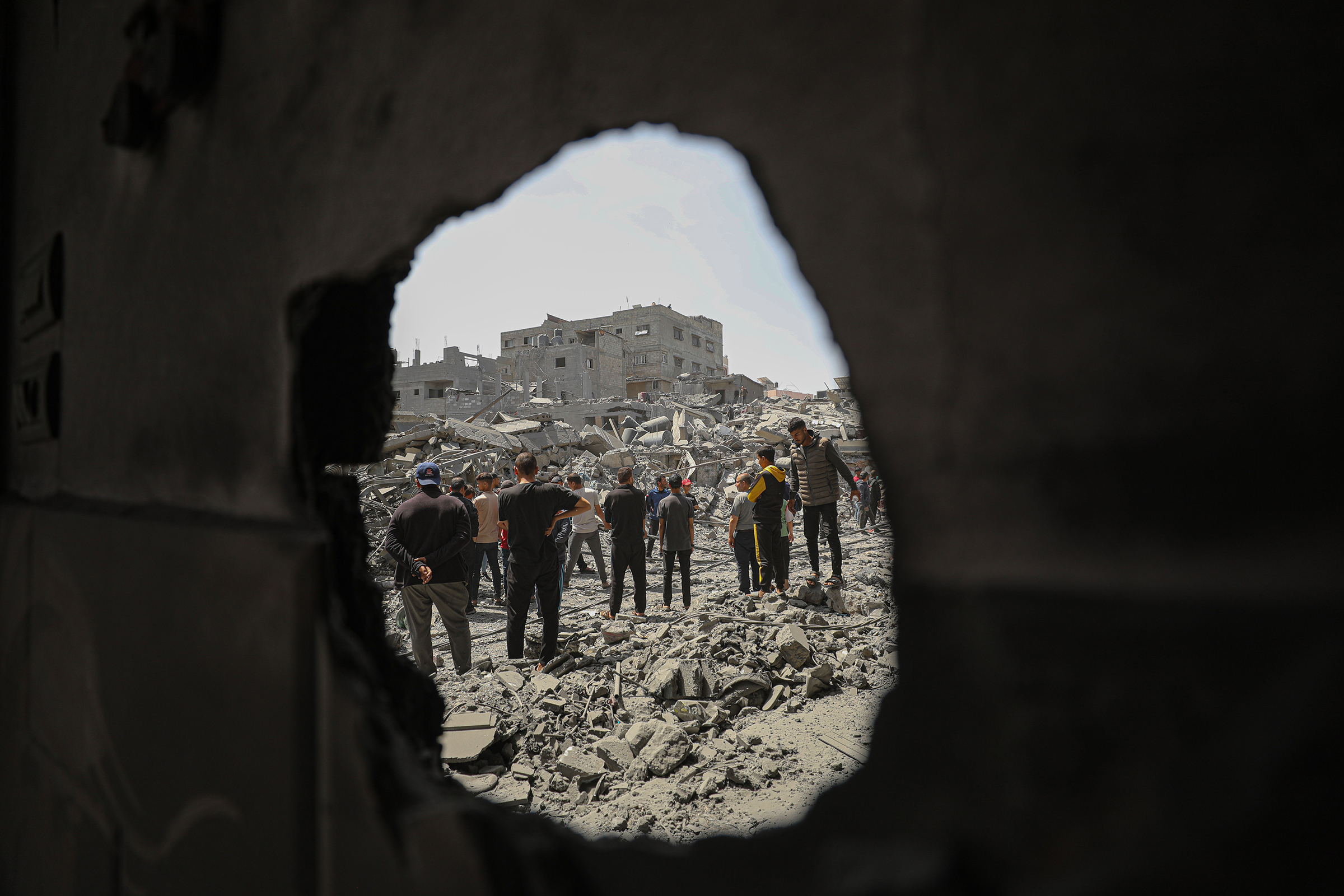 People look at damaged buildings and vehicles after an Israeli attack, in Gaza City, April 22, 2024.