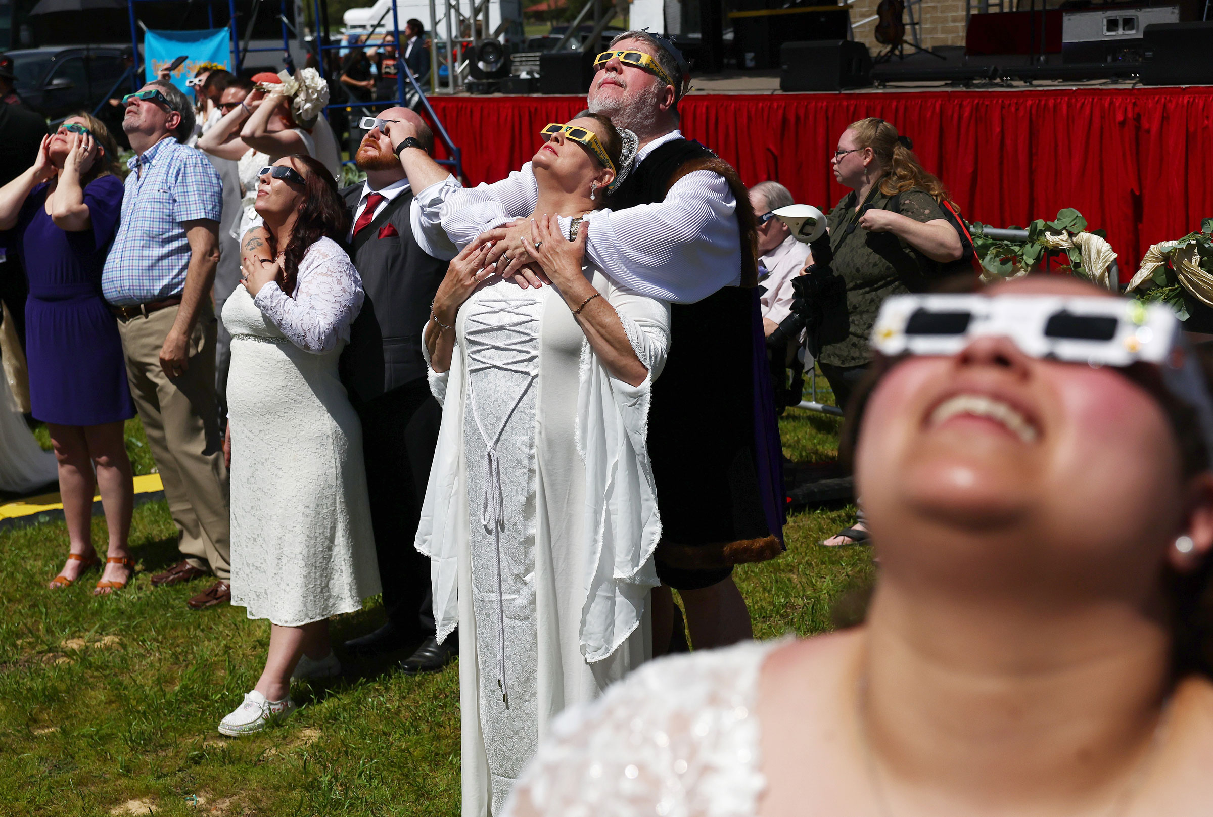 Couples view the solar eclipse during a mass wedding at the Total Eclipse of the Heart festival in Russellville, Ark.