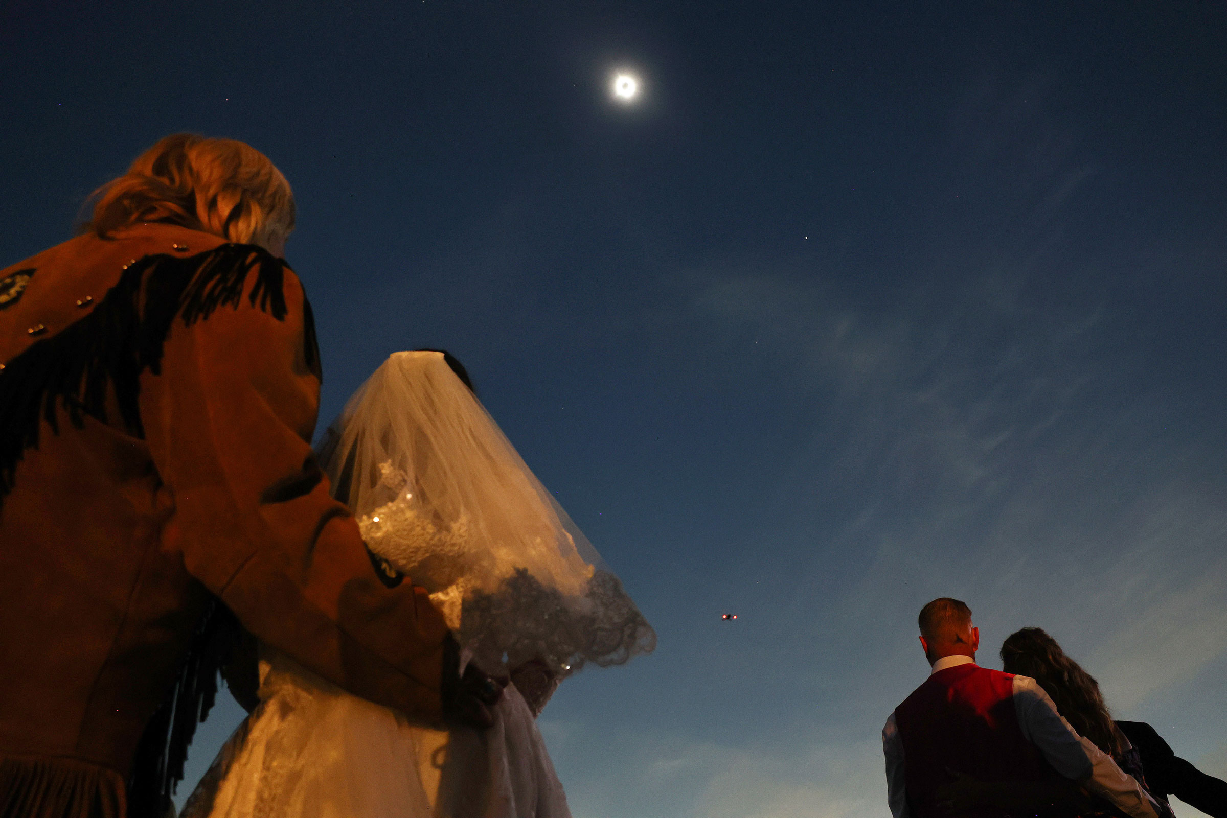 Couples view the solar eclipse during totality at a mass wedding at the Total Eclipse of the Heart festival in Russellville, Ark.