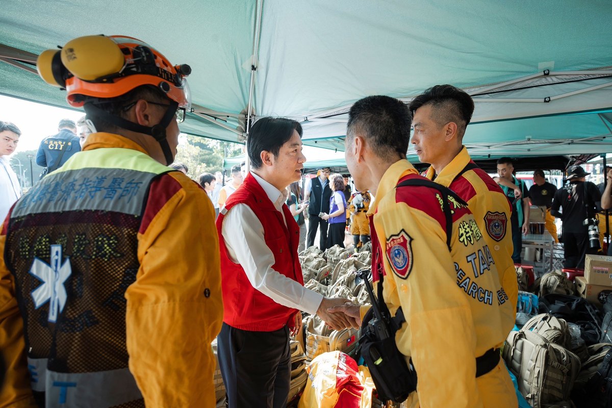 台湾当选总统兼副总统赖清德（中）在视察台湾东部地震灾区花莲市时与救援人员握手。