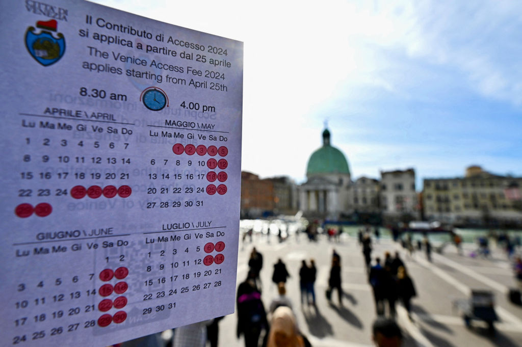 A person shows a calendar of the paying days to visit Venice, on April 19, 2024 in front of Santa Lucia train station in Venice. 