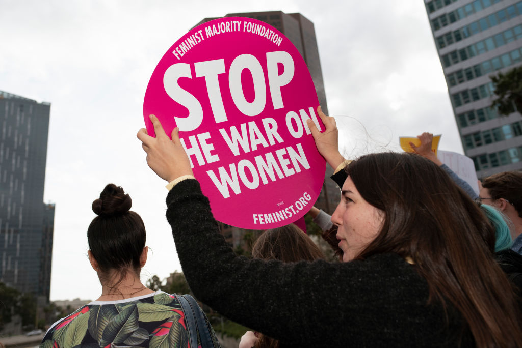 An activist seen holding a placard that says Stop The War On