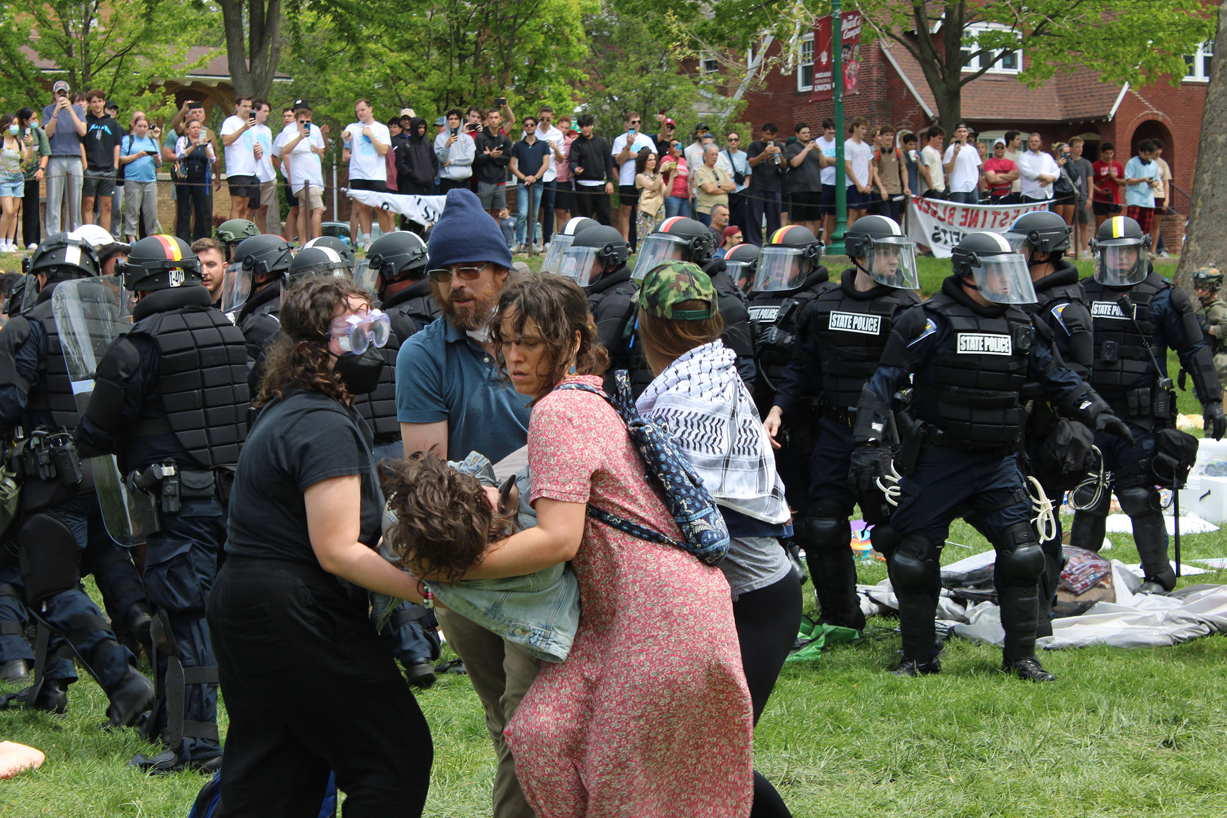 A medic and three demonstrators help a protester to the ground while Indiana State Police clear the encampment on April 27. There was a rotating crew of medics at the encampment.