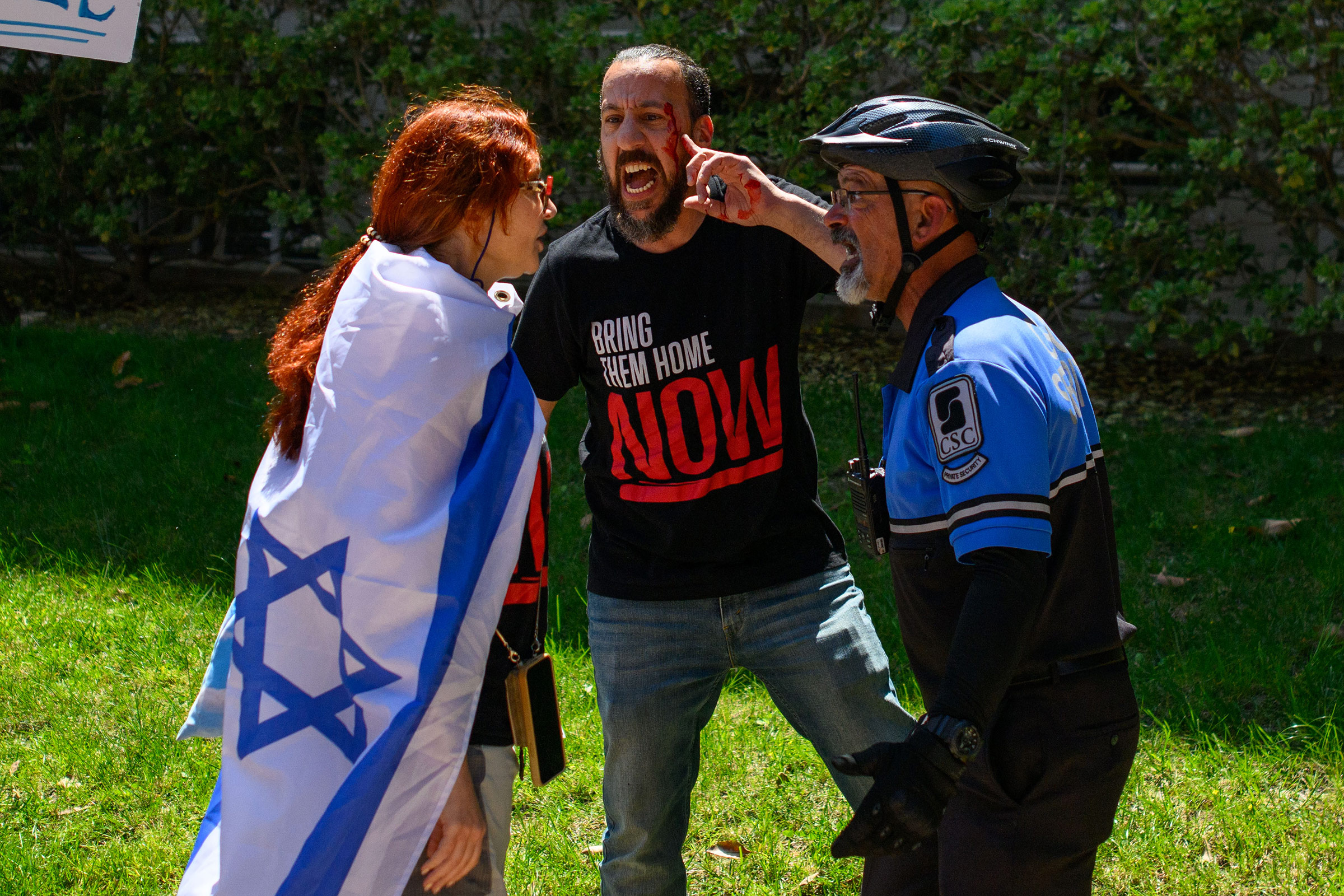 A counterprotester gestures to a bleeding injury on his eyebrow while talking to a Community Service Commission officer after an altercation on April 23.