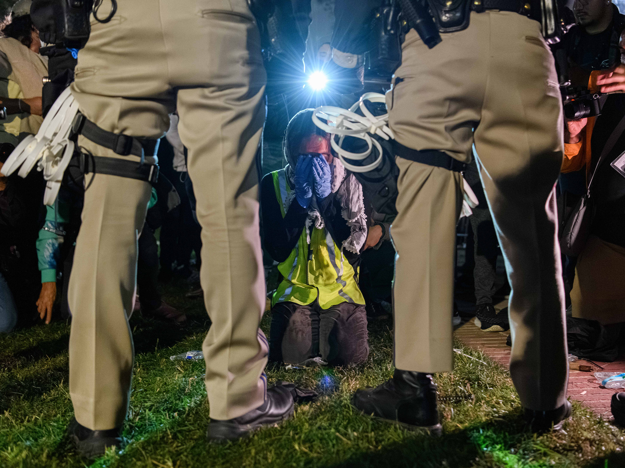 A pro-Palestinian protester kneels in front of two California Highway Patrol officers in Los Angeles on May 1.
