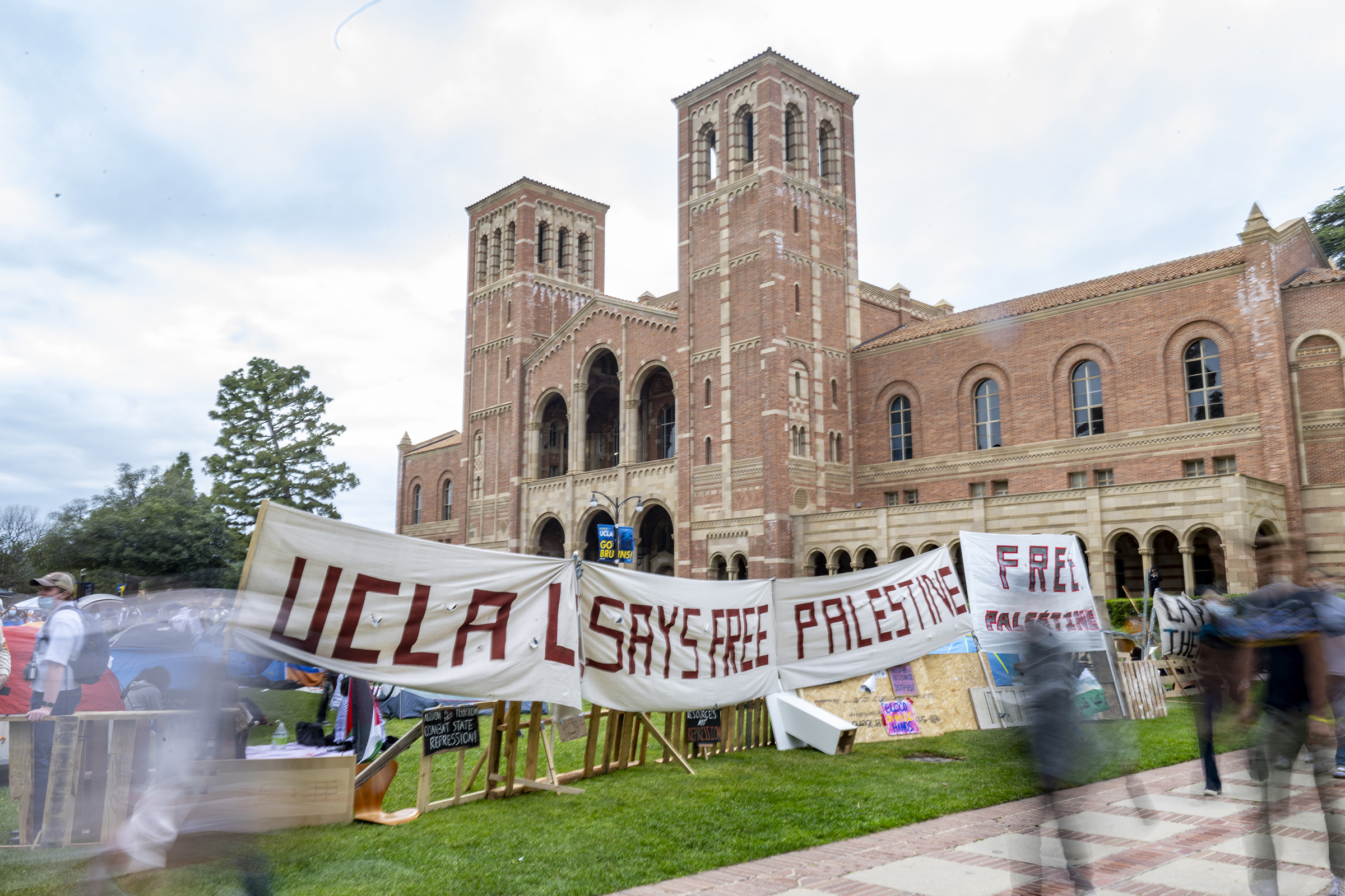 A poster reading “UCLA Says Free Palestine” hangs on the barrier of the pro-Palestinian encampment on April 25. The community expressed mixed sentiments toward the encampment, with some offering support and others voicing concerns.
