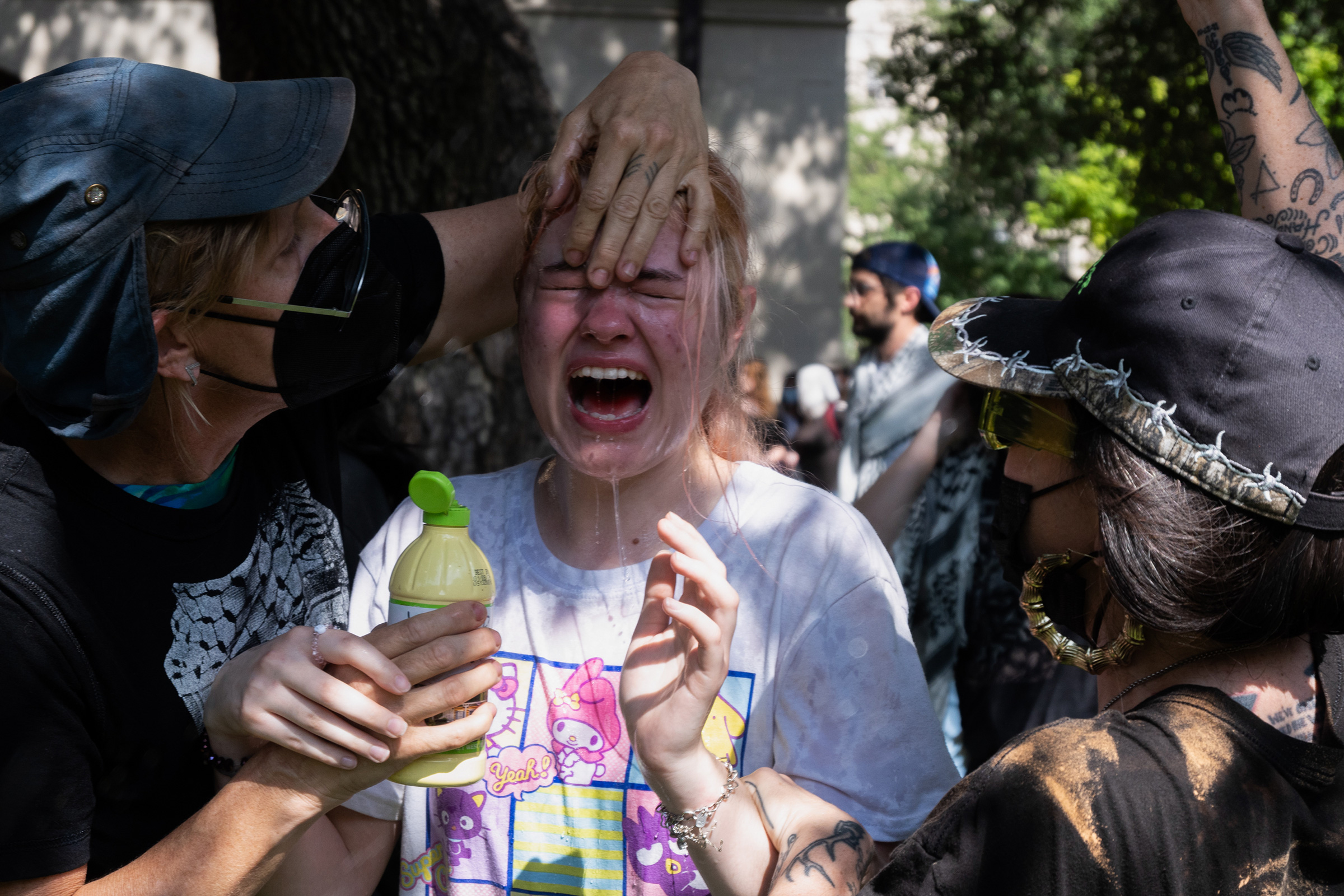 People pour liquid on someone's face to help relieve the pain of getting pepper-sprayed on UT Austin's campus on April 29.
